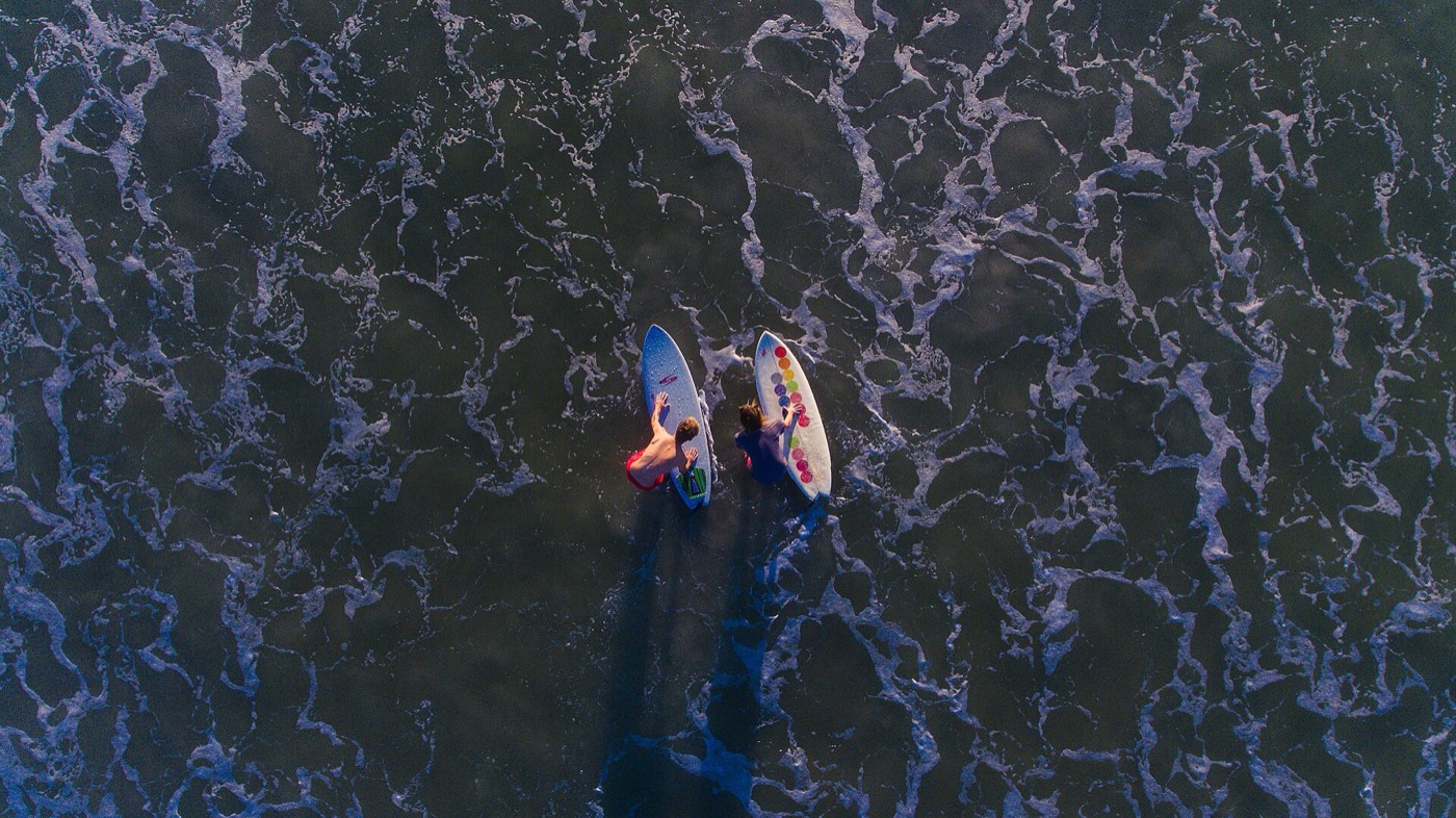 Deux surfeurs vus du dessus dans l'écume